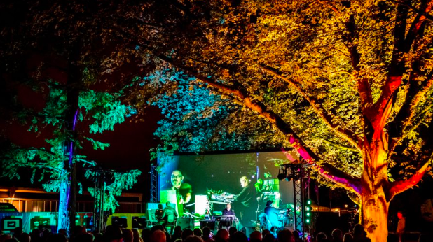 Een avondvoorstelling van Bert Barten, waarbij muziek van bomen wordt gecombineerd met kleurrijke verlichting en projecties. Het publiek geniet van deze unieke kunst- en natuurervaring.