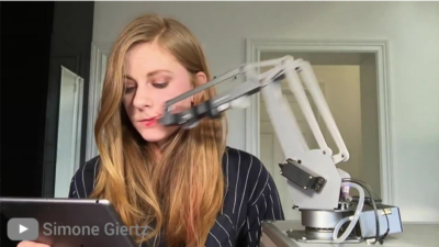 Voorbeeld van een waardeloze robot: Robotarm die Simone Giertz haar lippen stift.