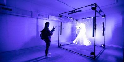 Lichtgevende jurk gemaakt van lichtgevend zijde, die ophangt in een kubus. Ontwerp van AnotherFarm, waarbij kunst en biologie met elkaar kruisen.